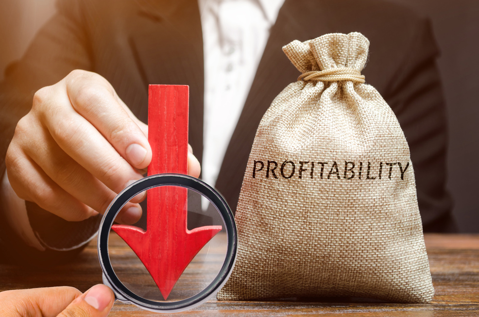 Bag with the word Profitability and a down arrow with a businessman. Low economic efficiency and profitableness. Drop in profits and earnings in a company. Unprofitability. Financial instability